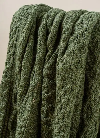 Close-up of dark green Aran throw draped across wooden chair
